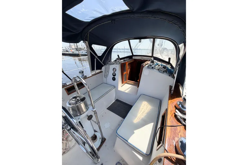 Slide: The Image of 1987 Bayfield 36 sailboat cockpit with seating, steering wheel, and marina view. - 16