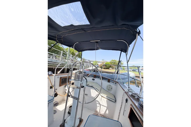 Slide: The Image of 1987 Bayfield 36 sailboat cockpit with steering wheel and canopy, docked at marina. - 21