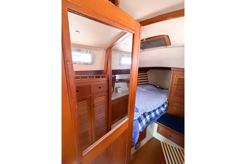 Slide: The Image of Cozy cabin interior of a 1987 Bayfield 36 sailboat with wooden furnishings and a comfortable bed. - 51