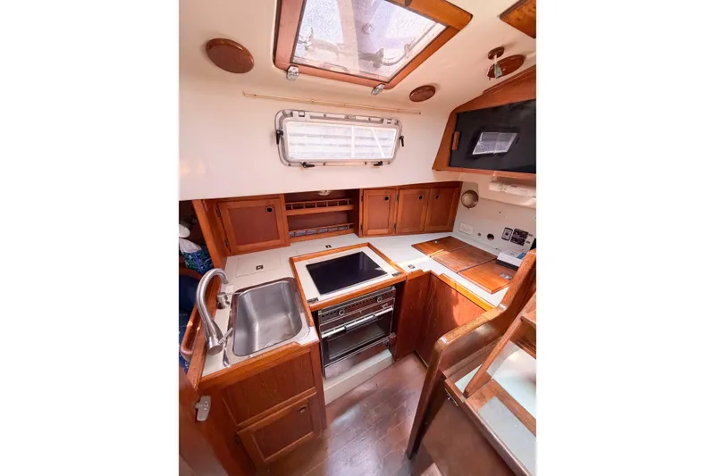 Slide: The Image of 1987 Bayfield 36 yacht interior kitchen with wooden cabinetry and stainless steel sink. - 57
