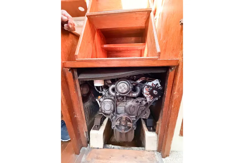 Slide: The Image of Engine compartment of a 1987 Bayfield 36 sailboat, showcasing mechanical components under wooden stairs. - 64