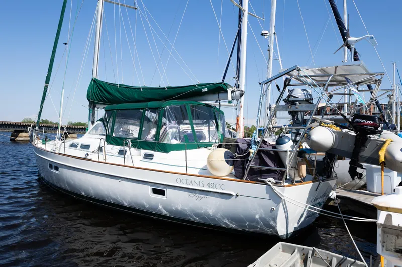 The Image of 2002 Beneteau Oceanis 42CC sailboat docked in marina, featuring green canopy and white hull. - 0