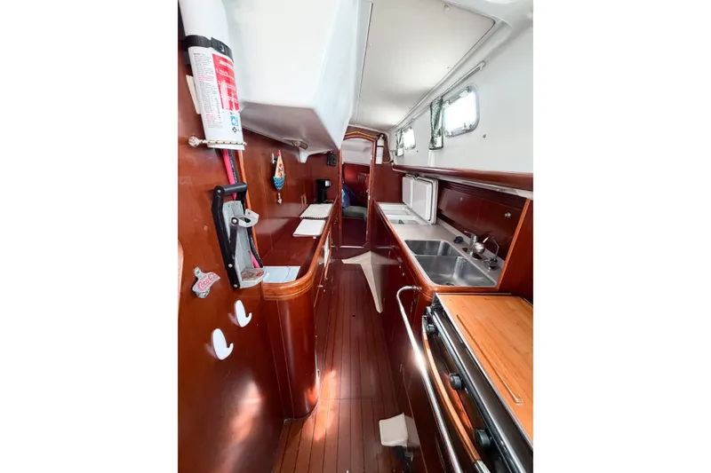 Slide: The Image of Interior of 2002 Beneteau Oceanis 42CC sailboat with wooden cabinetry and kitchen amenities. - 49