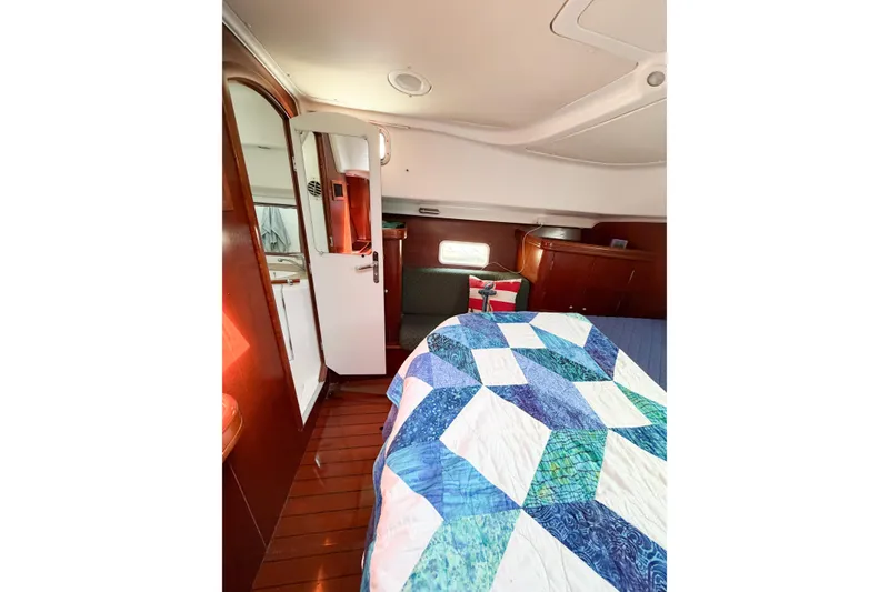 Slide: The Image of Interior of 2002 Beneteau Oceanis 42CC yacht with quilted bed and wooden cabinetry. - 52