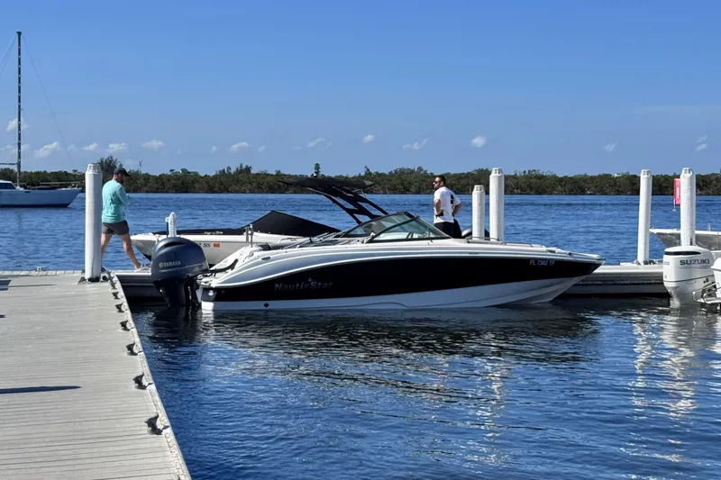 The Image of 2022 NauticStar 223DC Sport Deck boat with black canopy on display. - 1