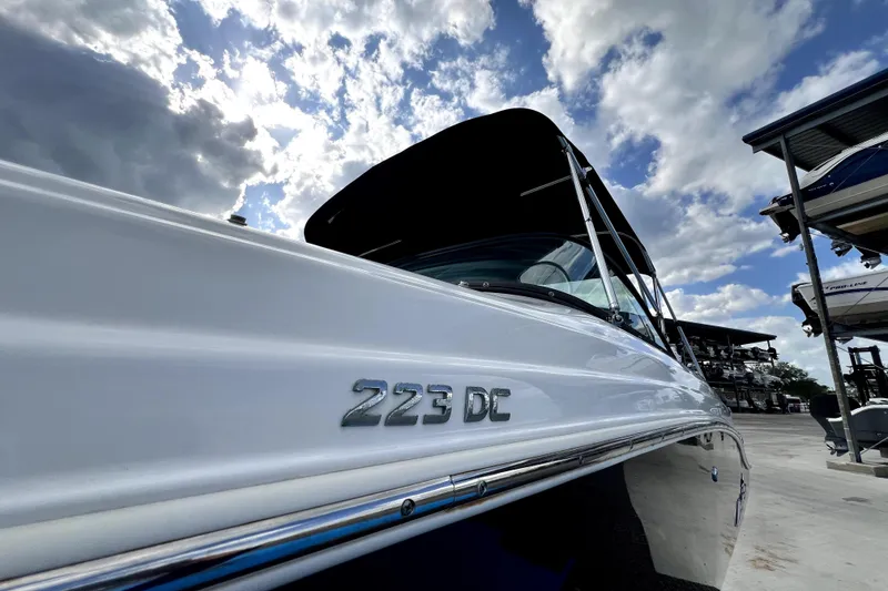 Slide: The Image of 2022 NauticStar 223DC Sport Deck boat under a cloudy sky. - 18
