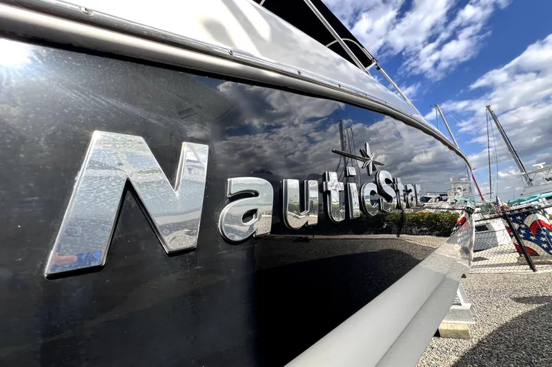 Slide: The Image of 2022 NauticStar 223DC Sport Deck boat with reflective logo under blue sky. - 19