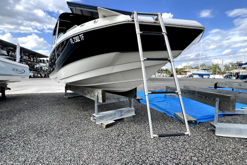Slide: The Image of 2022 NauticStar 223DC Sport Deck boat on trailer with ladder, under a blue sky. - 20