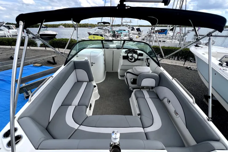 Slide: The Image of 2022 NauticStar 223DC Sport Deck boat with spacious seating and sleek design at a marina. - 23