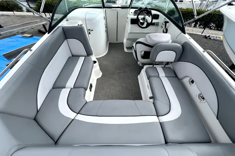 Slide: The Image of 2022 NauticStar 223DC Sport Deck interior with gray and white seating, steering console, and spacious layout. - 24