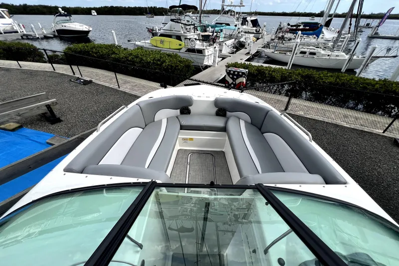 Slide: The Image of 2022 NauticStar 223DC Sport Deck boat with spacious seating, docked at a marina. - 27