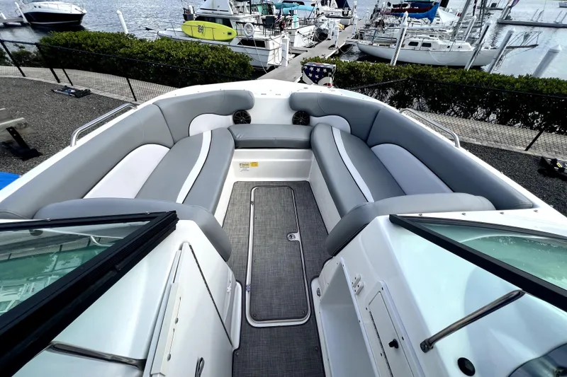 Slide: The Image of 2022 NauticStar 223DC Sport Deck boat interior with gray seating, docked at marina. - 29