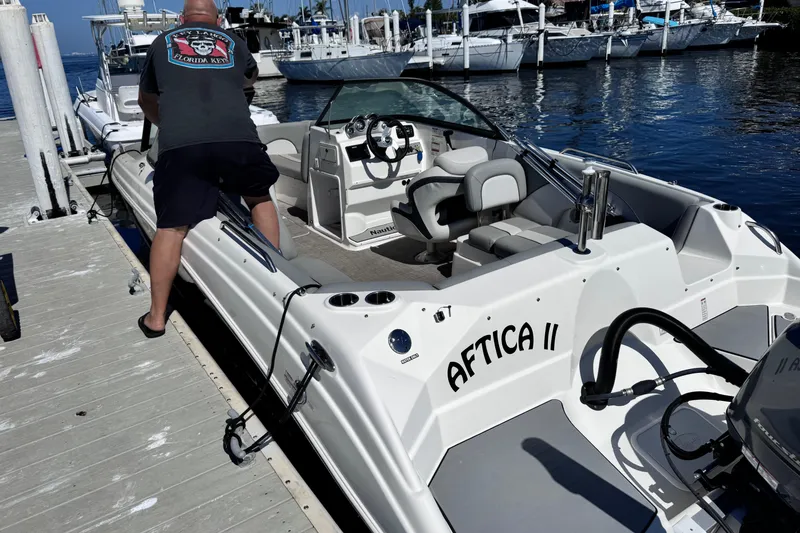 Slide: The Image of 2022 NauticStar 223DC Sport Deck boat with black canopy and Yamaha outboard motor. - 5