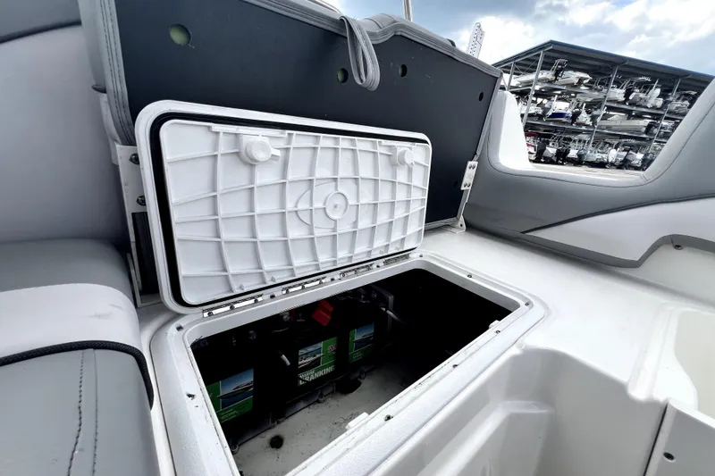 Slide: The Image of 2022 NauticStar 223DC Sport Deck boat battery compartment open, showcasing storage space. - 51