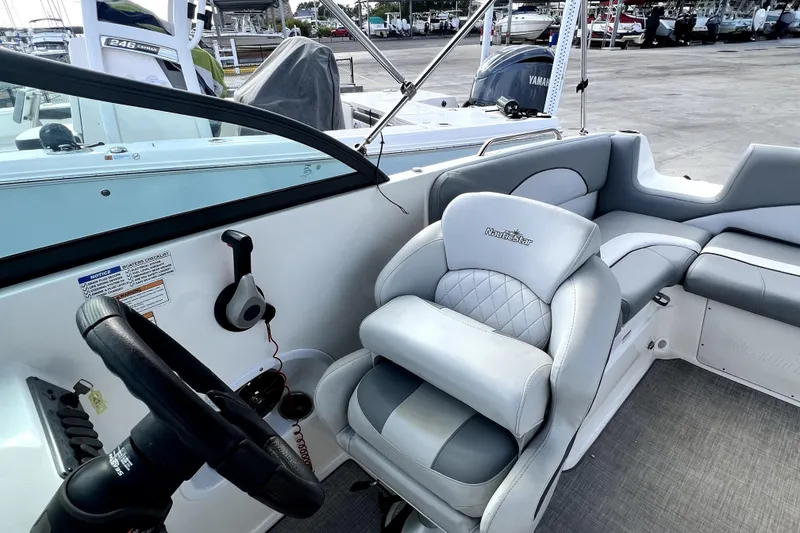 Slide: The Image of 2022 NauticStar 223DC Sport Deck boat interior with steering wheel and cushioned seating. - 70