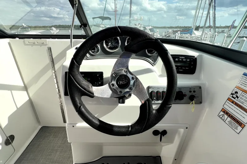 Slide: The Image of 2022 NauticStar 223DC Sport Deck steering wheel and dashboard controls. - 74