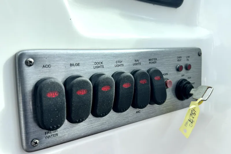 Slide: The Image of Control panel of 2022 NauticStar 223DC Sport Deck boat with labeled switches and key. - 78