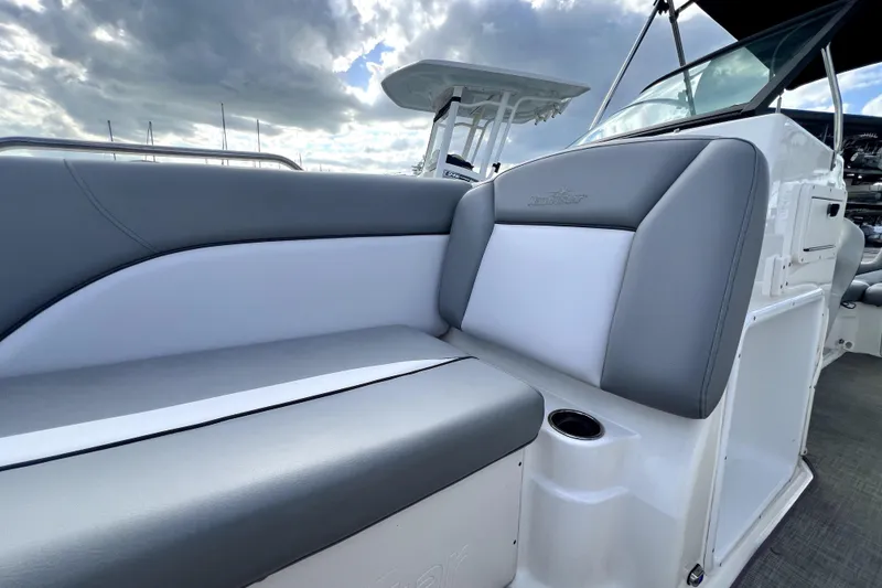 Slide: The Image of 2022 NauticStar 223DC Sport Deck boat with gray and white seating under cloudy sky. - 82
