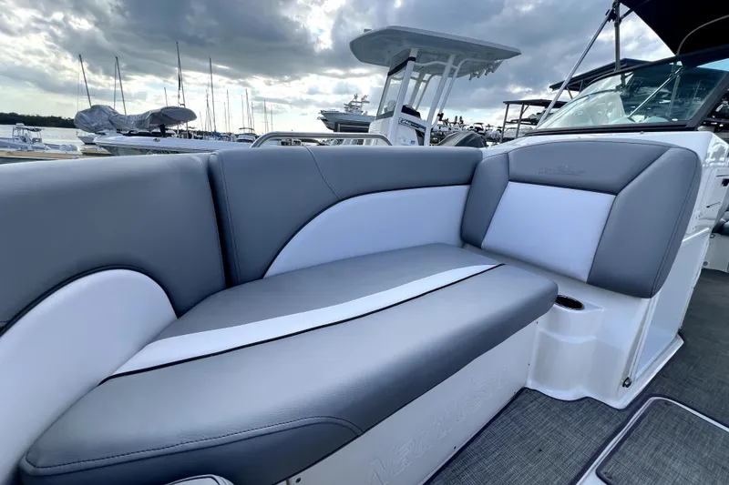Slide: The Image of 2022 NauticStar 223DC Sport Deck boat with sleek gray and white seating at a marina. - 83