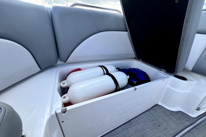 Slide: The Image of Storage compartment on 2022 NauticStar 223DC Sport Deck with fenders and life jackets. - 84