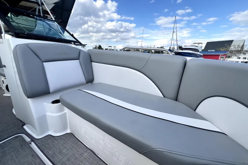 Slide: The Image of 2022 NauticStar 223DC Sport Deck boat with gray and white seating, docked under blue sky. - 90