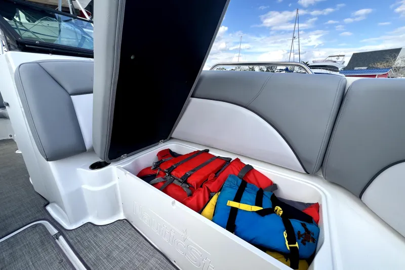 Slide: The Image of 2022 NauticStar 223DC Sport Deck boat with open storage compartment containing life jackets. - 91