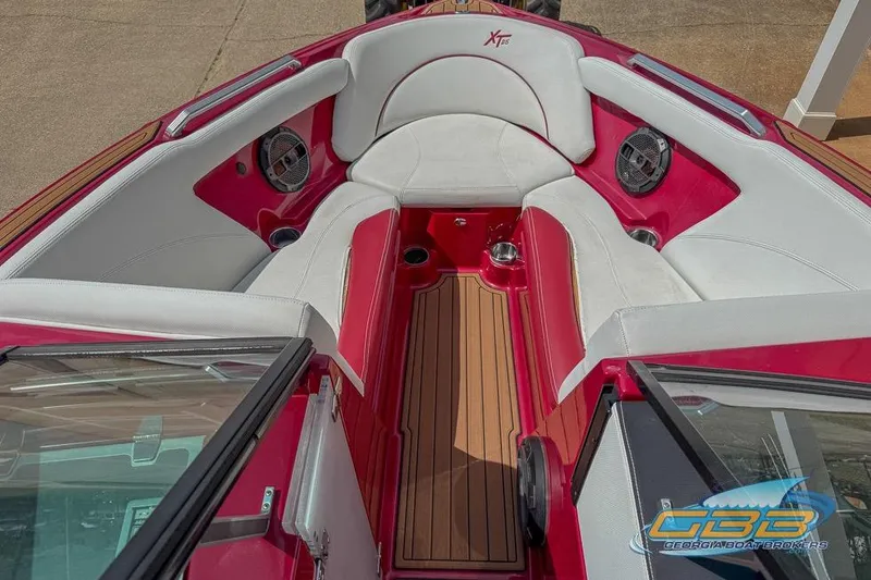 Slide: The Image of 2018 MasterCraft XT25 boat interior with red and white seating, wood flooring, and speakers. - 10