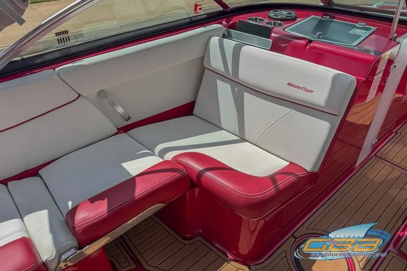 Slide: The Image of 2018 MasterCraft XT25 boat interior with red and white seating, featuring sleek design and wood flooring. - 13