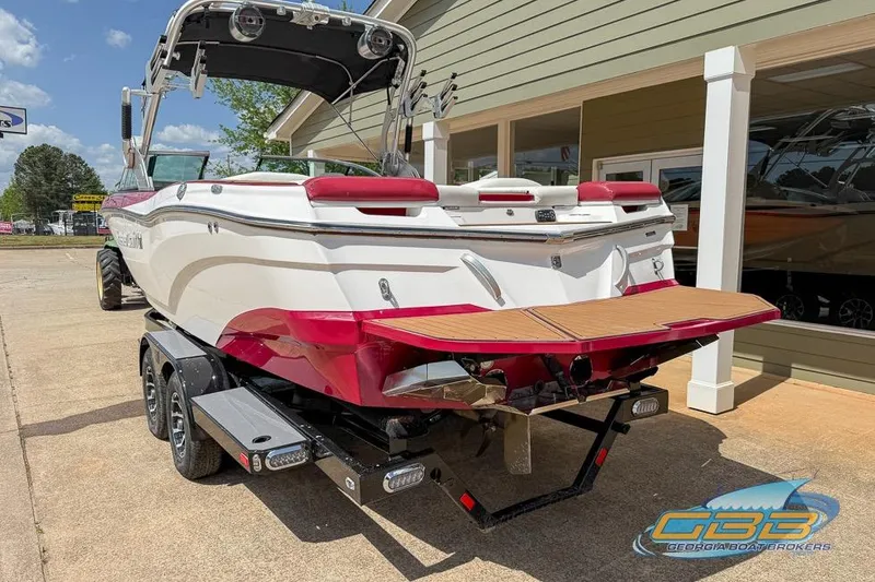Slide: The Image of 2018 MasterCraft XT25 boat on trailer, parked outside a building under a clear sky. - 18