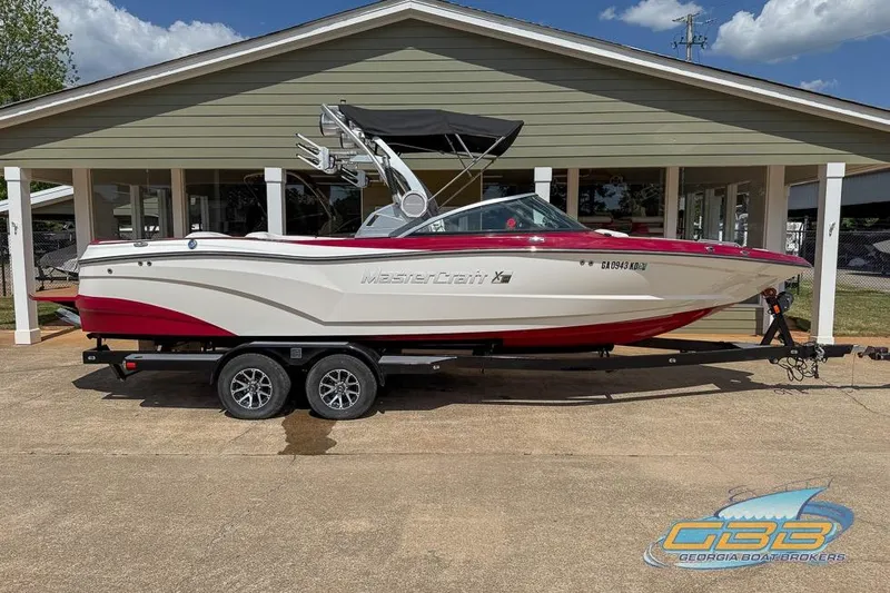 Slide: The Image of 2018 MasterCraft XT25 boat interior with red and white seating, wooden flooring. - 2