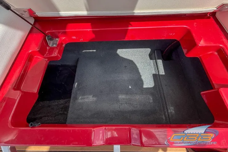 Slide: The Image of Red storage compartment in a 2018 MasterCraft XT25 boat, featuring a black interior. - 27