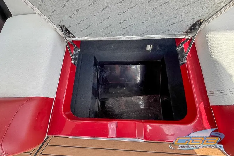 Slide: The Image of Open storage compartment in 2018 MasterCraft XT25 boat with red and white seating. - 29