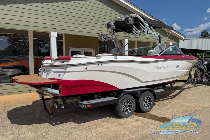 Slide: The Image of 2018 MasterCraft XT25 boat on trailer, white and red design, parked outside dealership. - 5
