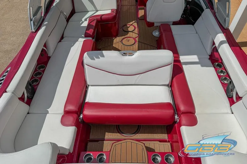 Slide: The Image of 2018 MasterCraft XT25 boat interior with red and white seating, wood flooring, and cup holders. - 7