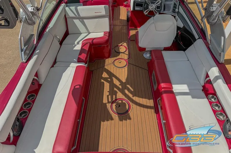 Slide: The Image of 2018 MasterCraft XT25 boat interior with red and white seating, wood flooring, and steering wheel. - 9