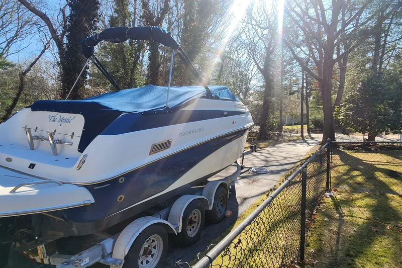 Slide: The Image of 2006 Crownline 236 SC boat on trailer, parked in a sunny wooded area. - 2