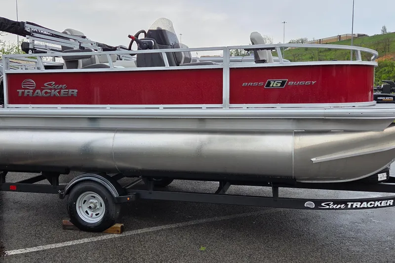 The Image of 2026 Sun Tracker Bass Buggy 16 XL Select pontoon boat on trailer, red and silver design. - 0