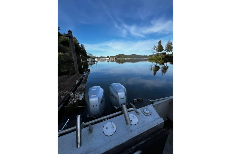 Slide: The Image of 1998 Maxweld Cuddy Hardtop boat with dual Honda 150 engines on a serene lake. - 20