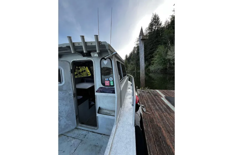 Slide: The Image of 1998 Maxweld Cuddy Hardtop boat docked by a wooden pier, surrounded by trees. - 23