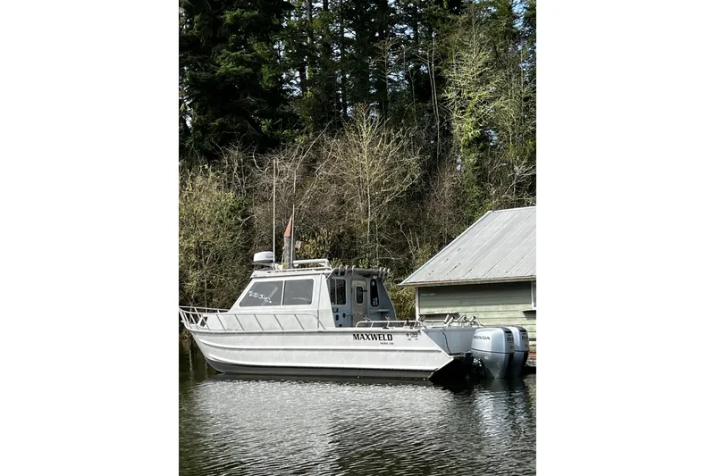 Slide: The Image of 1998 Maxweld Cuddy Hardtop boat docked near a forested shoreline. - 28