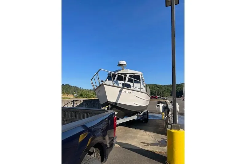 Slide: The Image of 1998 Maxweld Cuddy Hardtop boat on trailer, parked near a truck under clear blue sky. - 30