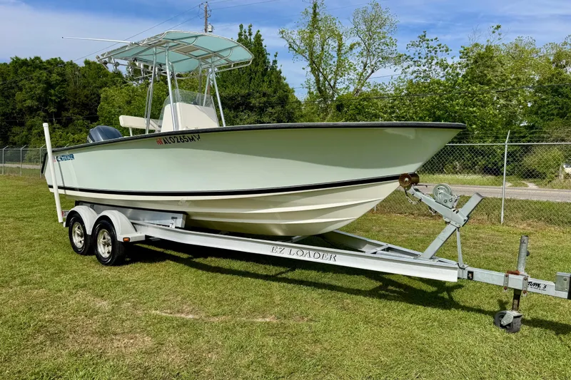 Slide: The Image of 2010 Contender 21 Open boat on trailer, parked on grass with trees in background. - 1