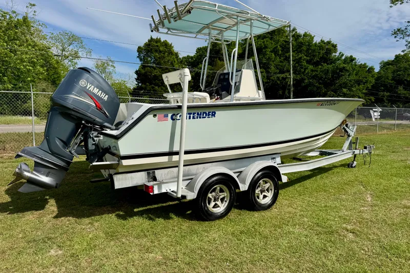 Slide: The Image of 2010 Contender 21 Open boat on trailer with Yamaha outboard motor, parked on grass. - 3