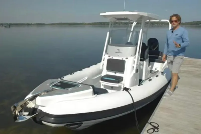 Slide: The Image of 2026 Highfield Escape 750 boat docked on calm water with a person standing nearby. - 2