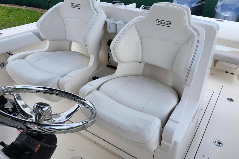 Slide: The Image of 2015 Robalo R300 Center Console boat with white cushioned seats and steering wheel. - 17
