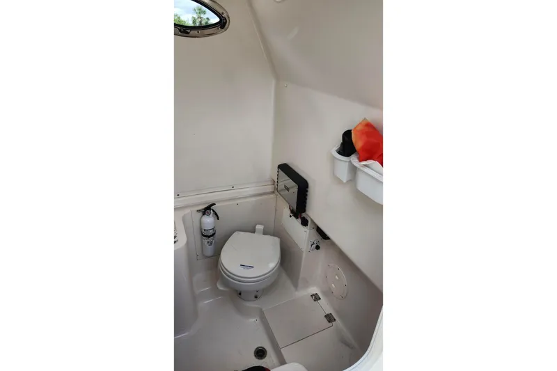 Slide: The Image of 2015 Robalo R300 Center Console boat interior with toilet and storage shelves. - 37