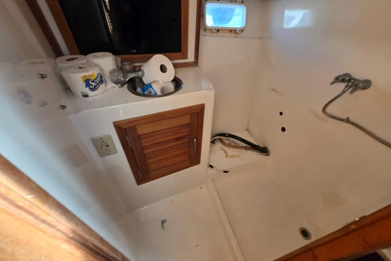 Slide: The Image of 1987 Topaz 29 Sportfisherman bathroom with sink, wooden cabinet, and shower area. - 10