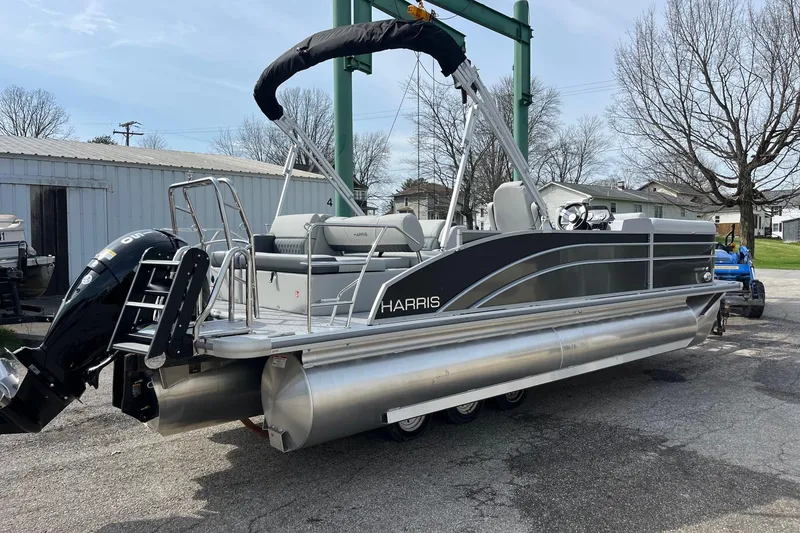 Slide: The Image of 2026 Harris Cruiser 230 SL pontoon boat with outboard motor, parked outdoors. - 2