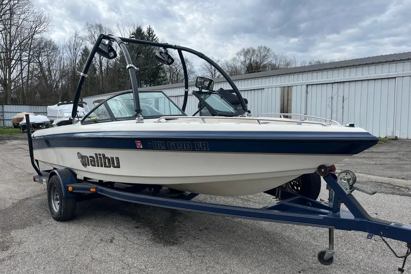 The Image of 2001 Malibu Sunsetter boat on trailer, parked outdoors under cloudy sky. - 1