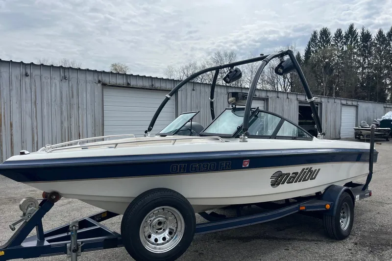Slide: The Image of 2001 Malibu Sunsetter boat on trailer, parked outdoors near storage units. - 7